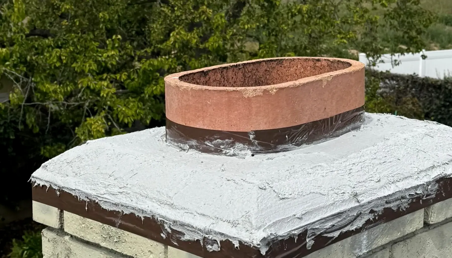 Brick chimney and roofline with trees behind it